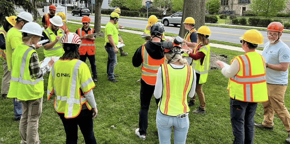 People taking notes while in safety gear as an instructor talks. 